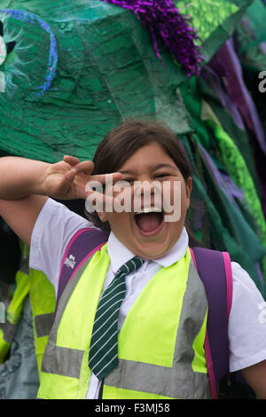 Falmouth, UK. Friday the 9th of October 2015.Girl carrying a dragon costume float shows a peace symbol at the Falmouth Oyster Festival Parade 2015 through Arwenack street in Falmouth. Credit:  Michael Hirst/Alamy Live News Stock Photo