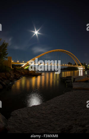 Illuminated arch bridge at night with a harvest moon.