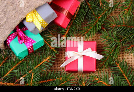 Wrapped colorful gifts for Christmas, birthday or other celebration in jute bag and spruce branches on jute canvas Stock Photo