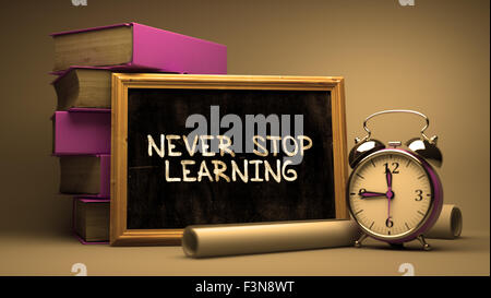 Never Stop Learning Handwritten by white Chalk on a Blackboard. Stock Photo