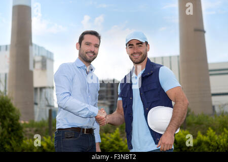 View of an Electrician and engineer handshaking in front of the electric station Stock Photo