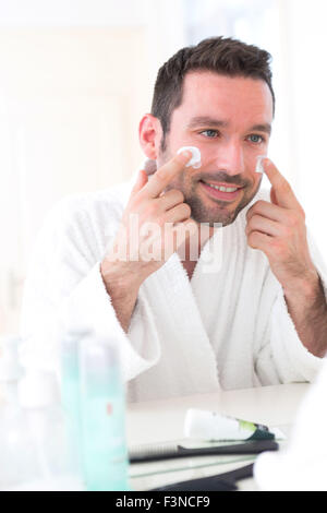 View of a Young attractive man applying anti dark circles cream around eyes Stock Photo
