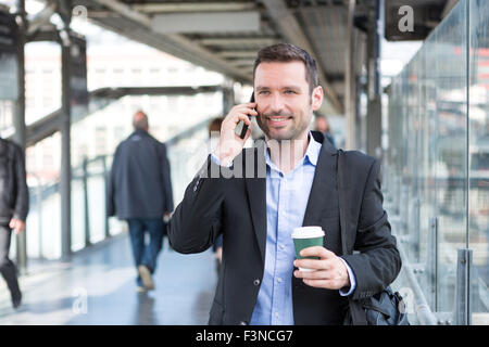 View of a Young attractive business man using smartphone while drinking coffee Stock Photo