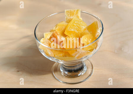 Dried sweet pieces of mango in bowl on wooden surface Stock Photo