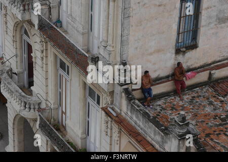 two constructros having a break on top of a house in Havana Stock Photo