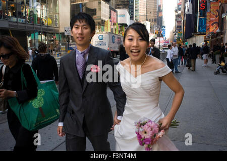 A newly married Asian couple celebrating their honeymoon in the area of Times Square. In the center of this spectacular combinat Stock Photo