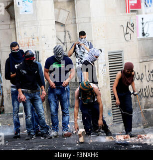 Masked Palestinian youth break rocks during clashes in the West Bank city of Hebron. Intense clashes between Palestinian youth and Israeli forces broke out in the West Bank city of Hebron, near the center of the city, known as Bab Al-Zawiye. The clashes followed the funeral of 19-year-old Muhammad Fares Abdullah al-Jaabari. The Palestinian youth was shot and killed by Israeli forces after he had allegedly stabbed an Israeli border guard in Kiryat Arba, an illegal Israeli settlement only kilometers away from Hebron. Al-Jaabri's funeral was only hours after another Palestinian youth, 20-year-old Stock Photo