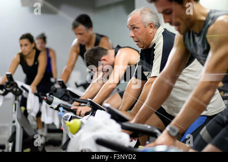 Side view of people riding stationary bicycles during a spinning class at the gym Stock Photo