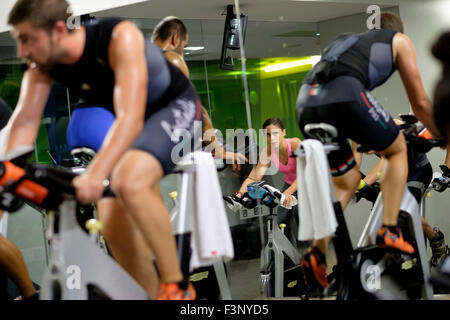 Young woman riding stationary bicycle during a spinning class at the gym Stock Photo