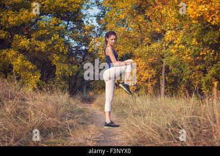 Young beautiful girl sports in the autumn forest at sunset Stock Photo