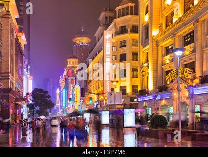 pedestrian walking shopping Nanking road street in Shanghai, China, at night with brightly lit by neon illimination lights of ad Stock Photo