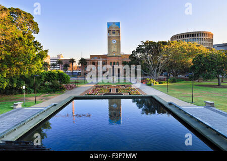 townhall of the city of Newcastle behind still pool in a park decorated by blooming flowers at sunrise Stock Photo