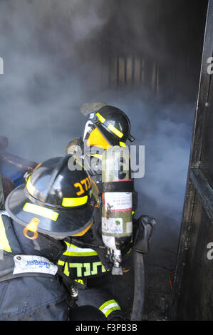 Firefighters with protective equipment in a smoke filled room Stock Photo