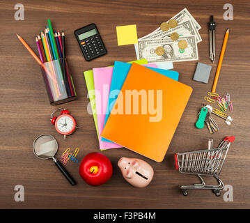 Shopping cart with office supplies and piggy bank Stock Photo