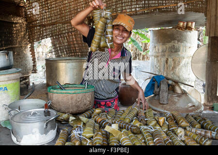 A woman cooking Rice ingots, wrapped in banana leaves - traditional Cambodian food. Stock Photo