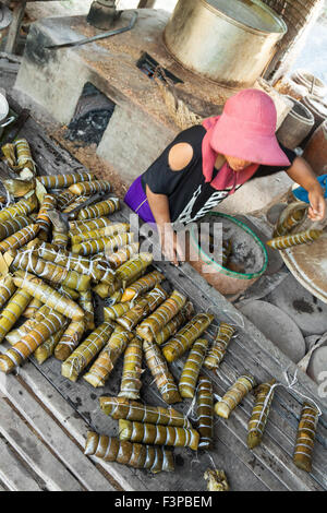 A woman cooking Rice ingots, wrapped in banana leaves - traditional Cambodian food. Stock Photo