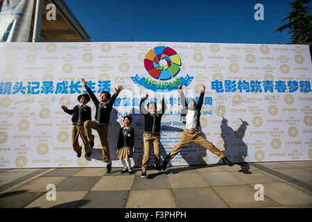 Beijing, China. 11th Oct, 2015. Students pose for photos in front of a poster of the 1st National Film Week for Primary and Middle School Students in Beijing, capital of China, Oct. 11, 2015. The 1st National Film Week for Primary and Middle School Students, which is themed with 70th anniversary of the victory of Chinese People's War of Resistance against Japanese Aggression and World War II, kicked off in Beijing 101 Middle School on Sunday. © Shen Bohan/Xinhua/Alamy Live News Stock Photo