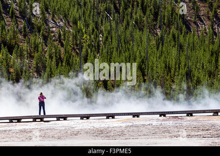 Park visitors walk on the boardwalk along Grand Prismatic Spring, Midway Geyser Basin, Yellowstone National Park, Wyoming, USA Stock Photo