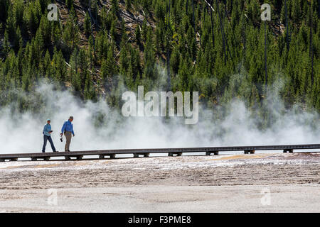 Park visitors walk on the boardwalk along Grand Prismatic Spring, Midway Geyser Basin, Yellowstone National Park, Wyoming, USA Stock Photo
