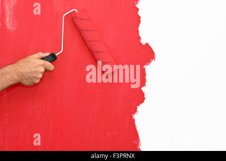 Painting a wall using a roller with red paint Stock Photo