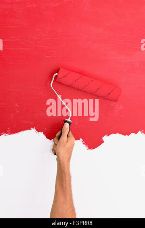 Painting a wall using a roller with red paint Stock Photo