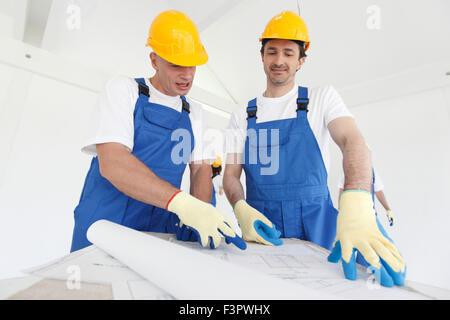 Workers in workwear looking at construction plan Stock Photo