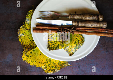 Autumnal table setting with vintage table silverware and yellow leaves Stock Photo