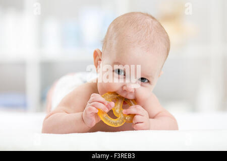 baby girl lying on belly weared diaper with teether Stock Photo