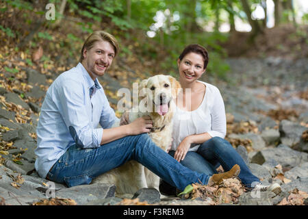 Couple sitting in the forest with Labrador Stock Photo