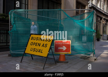 A sign saying that Business Open As Usual stands in a narrow City of London street. Stock Photo
