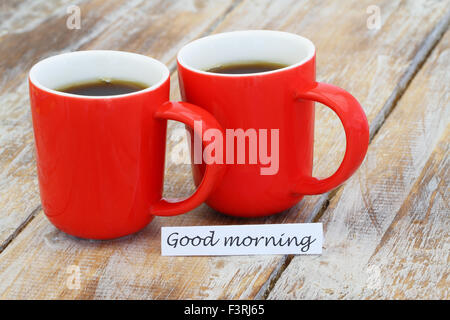 Good morning card with two red coffee mugs on rustic wooden surface Stock Photo