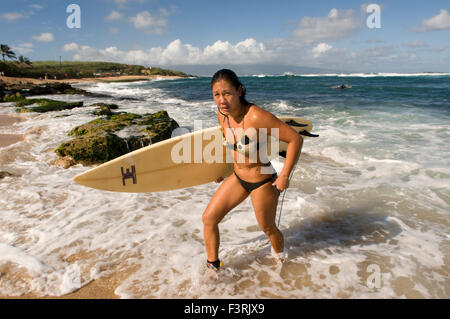 Woman Surfer leaving the water. Ho’okipa Beach. Maui. Hawaii. One of the world’s best windsurfing beaches, Hookipa is also a fav Stock Photo