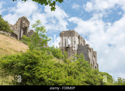 The hilltop ruins of Corfe Castle in Corfe, Dorset, south-west England on a sunny day with blue sky and fluffy white clouds
