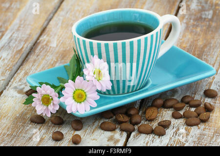 Cup of coffee and pink daisy flowers on rustic wooden surface Stock Photo