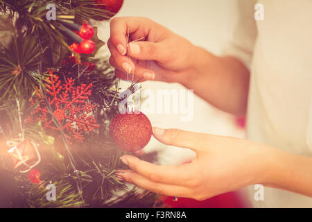 Woman hanging christmas decorations on tree Stock Photo