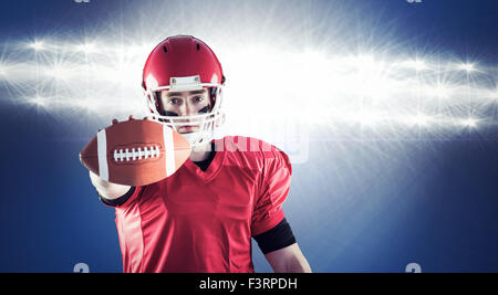 Composite image of portrait of american football player showing football to camera Stock Photo