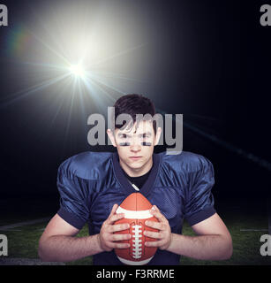 Composite image of determined american football player holding a ball Stock Photo