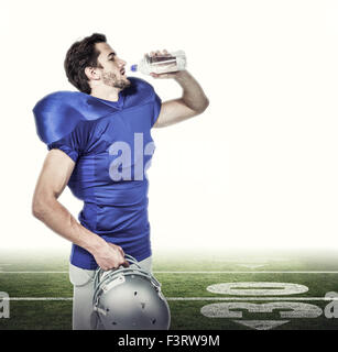 Composite image of american football player holding helmet while drinking water Stock Photo