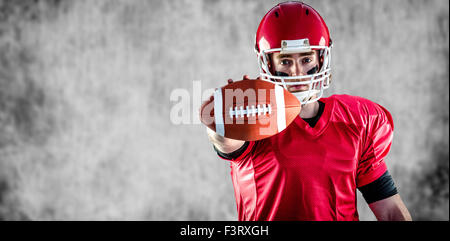 Composite image of portrait of american football player showing football to camera Stock Photo