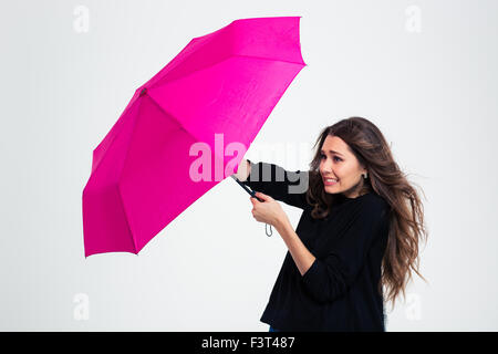 Portrait of a young woman holding umbrella in a strong wind isolated on a white background Stock Photo