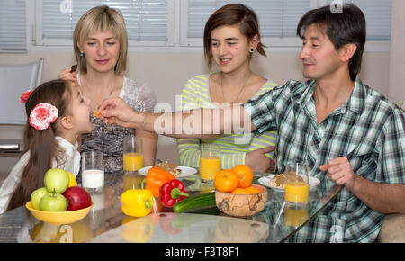 Family Sitting At Table Eating Meal Together Stock Photo