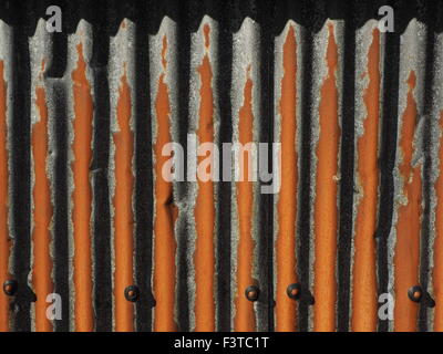 pattern produced by strong sunlight on rusty galvanised corrugated sheet metal with fixings Stock Photo