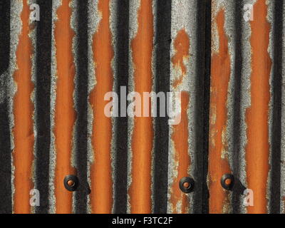 pattern produced by strong sunlight on rusty galvanised corrugated sheet metal with fixings Stock Photo