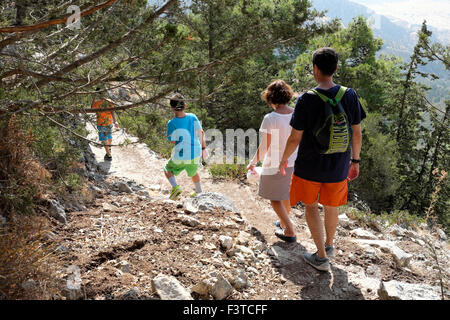 Rear view of a family of hikers walking down the steep path from Buffavento Castle  on a hike in the Besparmak Mountains in North Cyprus  KATHY DEWITT Stock Photo