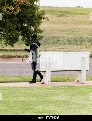 A young, pretty African American woman waits for a bus at a bus stop in Oklahoma City, Oklahoma, USA. U.S., U.S.A. Stock Photo