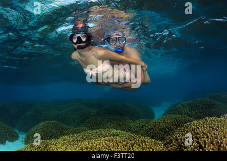 Young beautiful woman floats on the surface of the water over the coral reef, Indian Ocean, Maldives Stock Photo