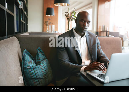 Portrait of young african businessman working on laptop in cafe. man sitting on hotel coffee shop. Stock Photo
