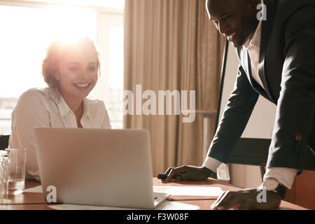 Portrait of happy young business team working together on laptop. Businessman and businesswoman meeting in conference room. Stock Photo