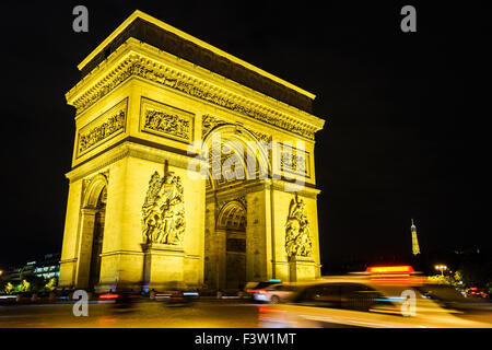 A taxi flashes by the Arc de Triomphe on a summer night, the Eiffel Tower stands in the background. Paris, France. August, 2015. Stock Photo