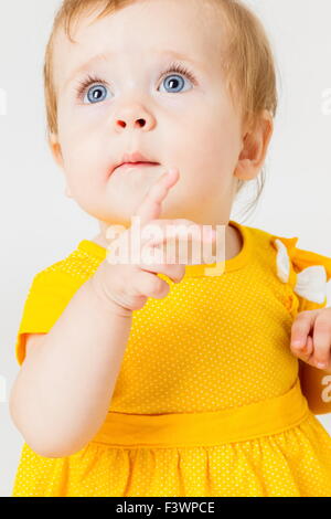 Little girl in the yellow dress on a light background. Stock Photo
